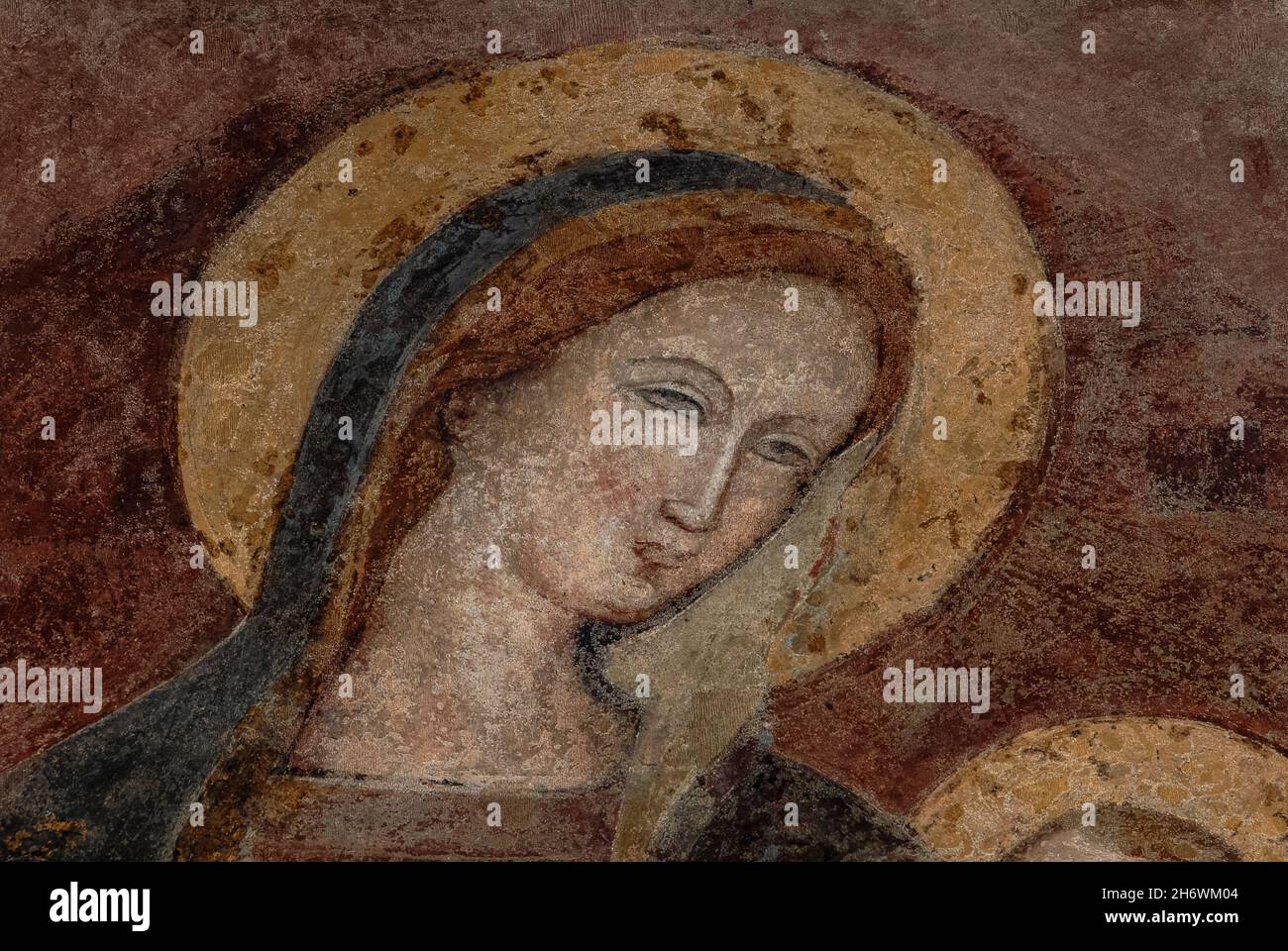Maria con gli occhi di mandorla e alone dorato nei minimi dettagli dell'affresco Lombardo della Vergine tardo medioevale con bambino. Nella ex Chiesa dei Santi Giovanni e Reparata (Chiesa dei Santi Giovanni e Reparata) a Lucca, Toscana, Italia. Foto Stock