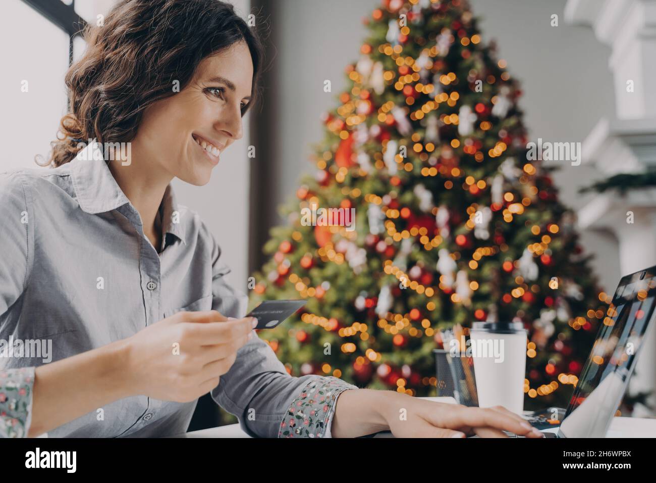 Felice giovane donna che fa lo shopping in linea sul computer portatile a casa durante le vendite di vacanze invernali Foto Stock