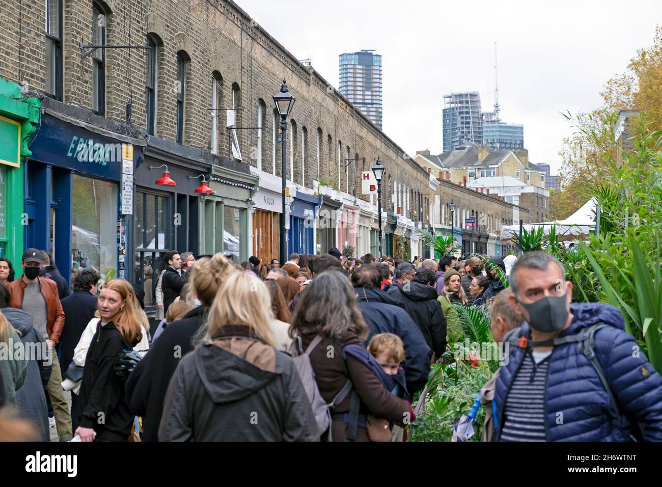 Columbia Road Flower Market People piante fiori in Street man maschera covid viso al mercato bancarelle Domenica di novembre 2021 East London UK KATHY DEWITT Foto Stock