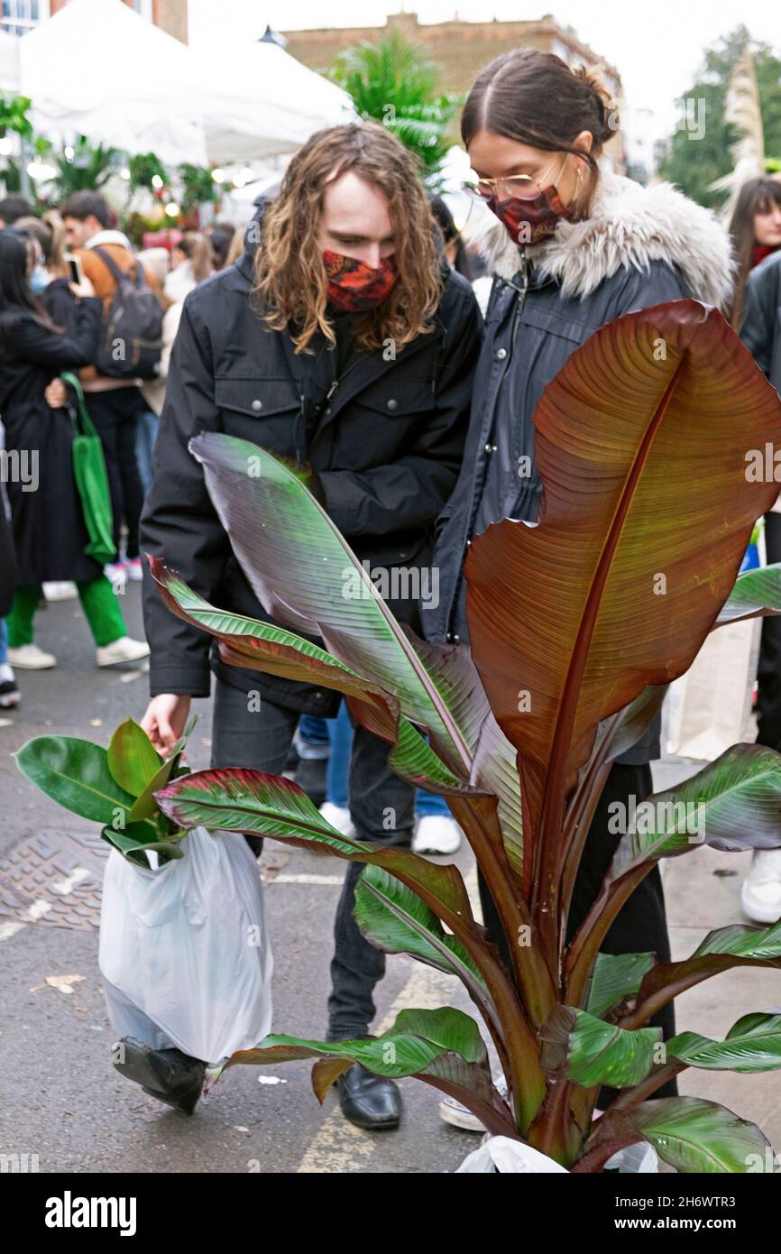 Columbia Road Flower Market persone che acquistano piante fiori che indossano maschere facciali covid in strada nel novembre 2021 East London UK KATHY DEWITT Foto Stock