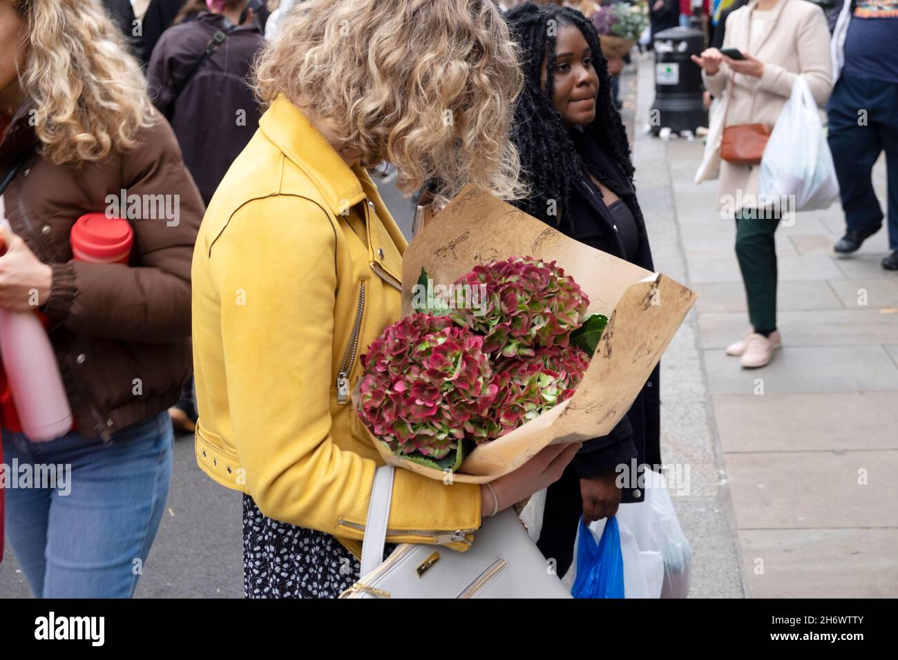 Columbia Road Flower Market donna con fiori di ortangea tagliati in strada al mercato bancarelle Domenica nel novembre 2021 East London UK KATHY DEWITT Foto Stock