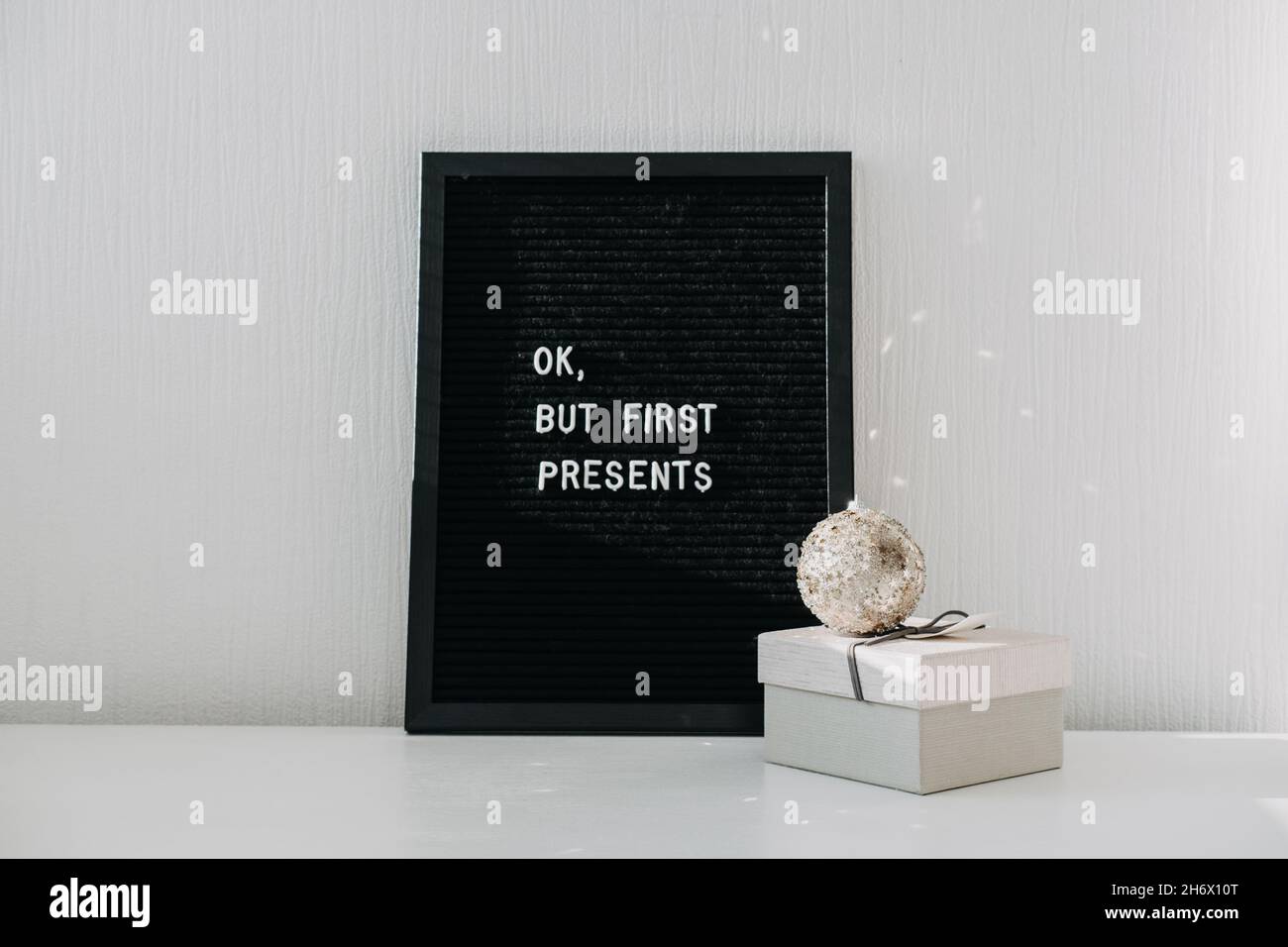 Banner web minimo di Natale con una scatola regalo di Natale e bordo nero lettera con preventivo OK, ma prima presenta. Idee di bordo della lettera di Natale festivo Foto Stock