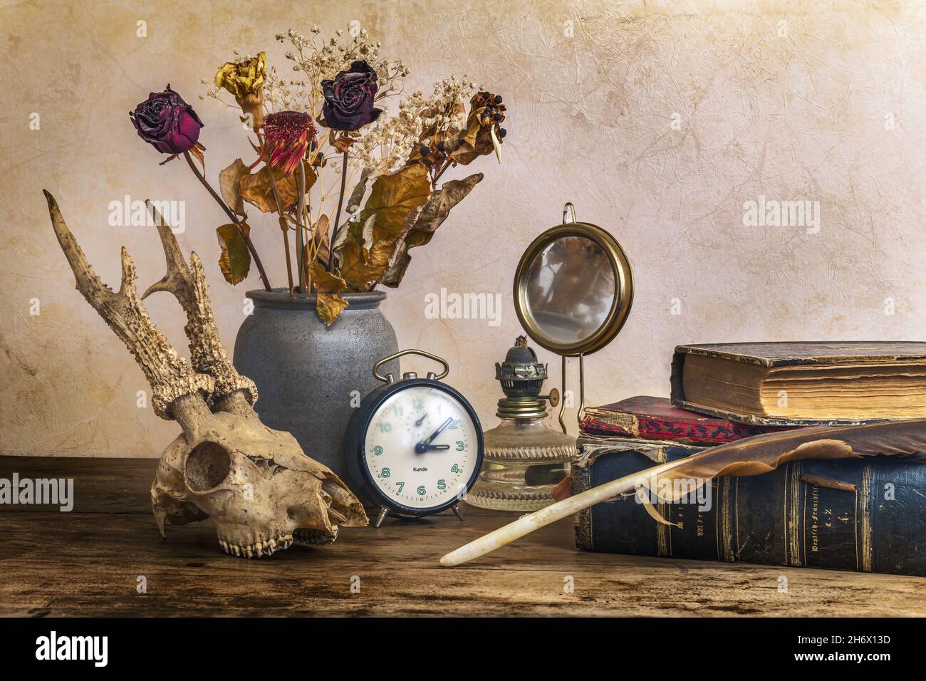La vita morta che esprime il passaggio del tempo con vecchi libri d'epoca, una lampada a cherosene, un bouquet di fiori e un cranio cervi. Foto Stock
