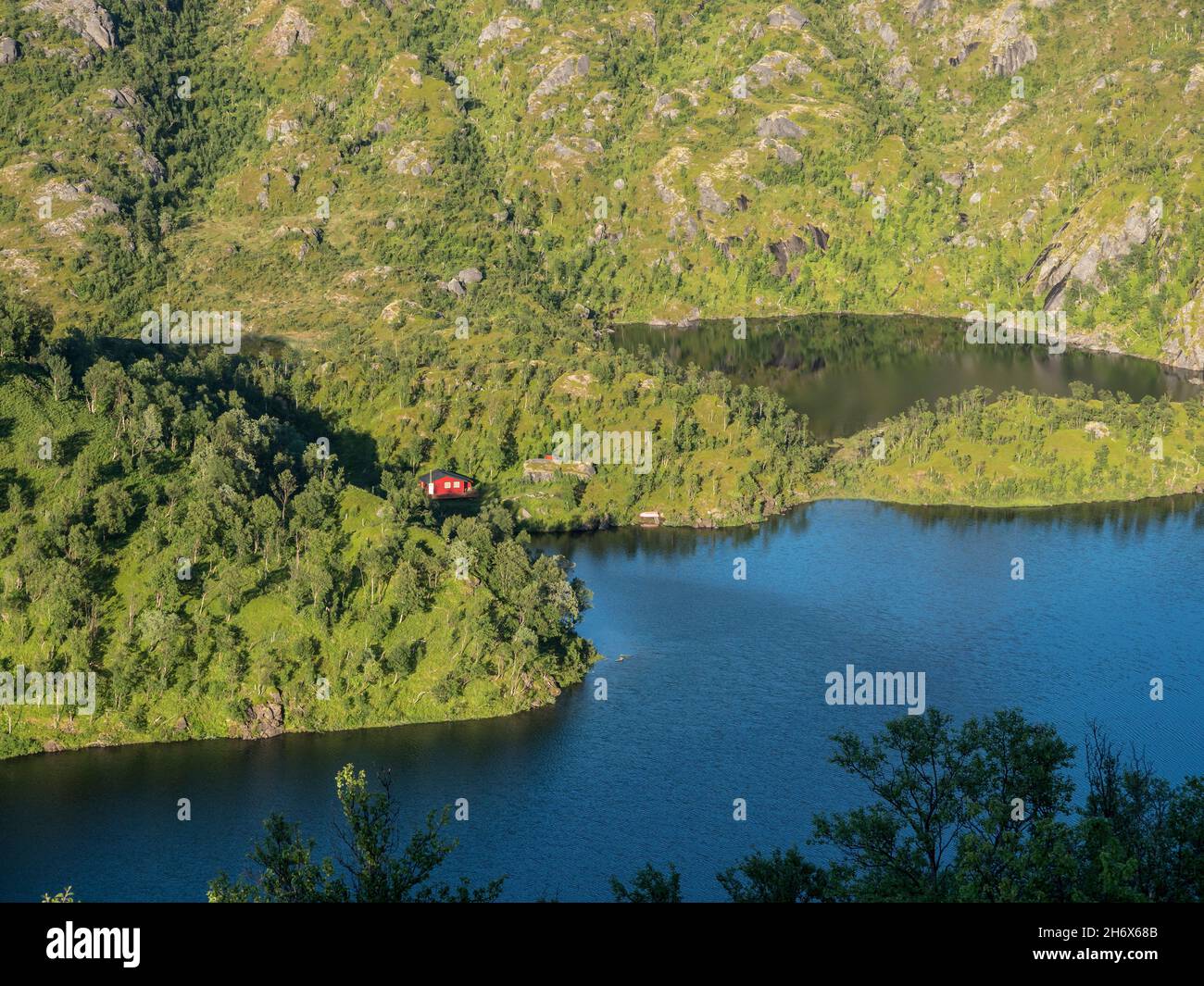 Cabina rossa solitaria al lago vicino mt. Sukkkertoppen, la montagna vicino a Hamn i Senja, Senaj isola, Norvegia Foto Stock