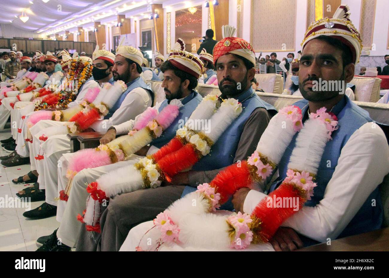 Foto di gruppo dei bridegrooms durante la cerimonia di matrimonio di massa organizzata dalla Fondazione al-Khidmat tenutasi a Peshawar giovedì 18 novembre 2021. Foto Stock