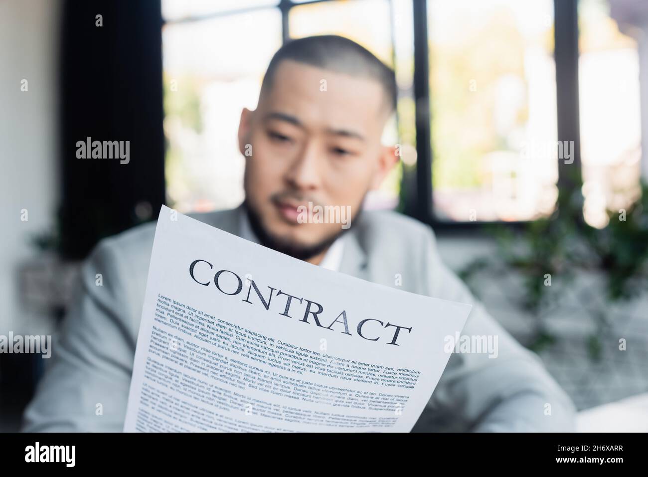 offuscato il contratto di lettura di un uomo d'affari asiatico in ufficio Foto Stock