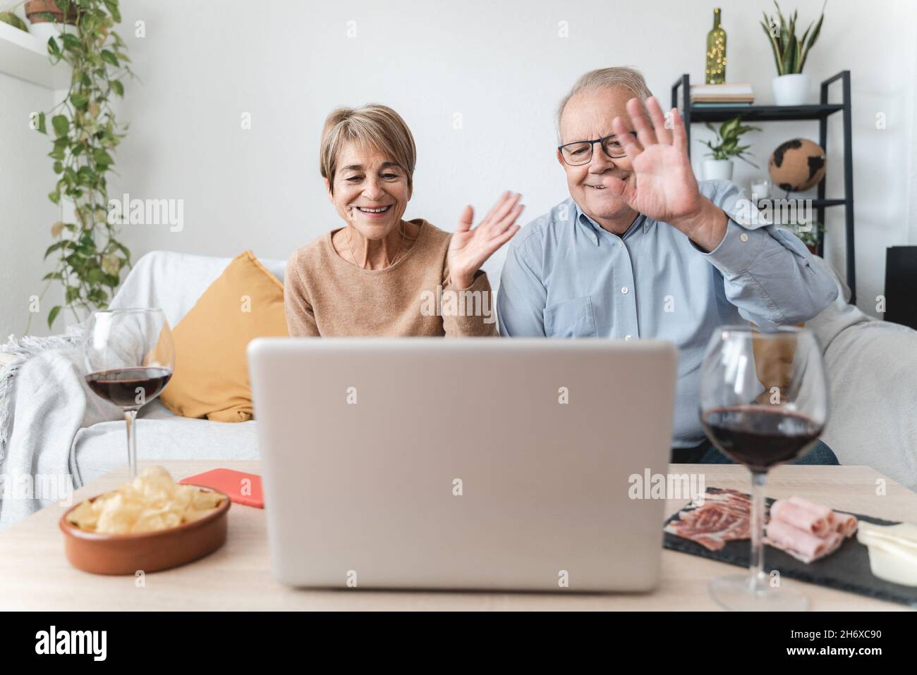 Coppia anziana che fa la videochiamata che festeggia con la famiglia nel paese - fuoco sul volto della donna Foto Stock