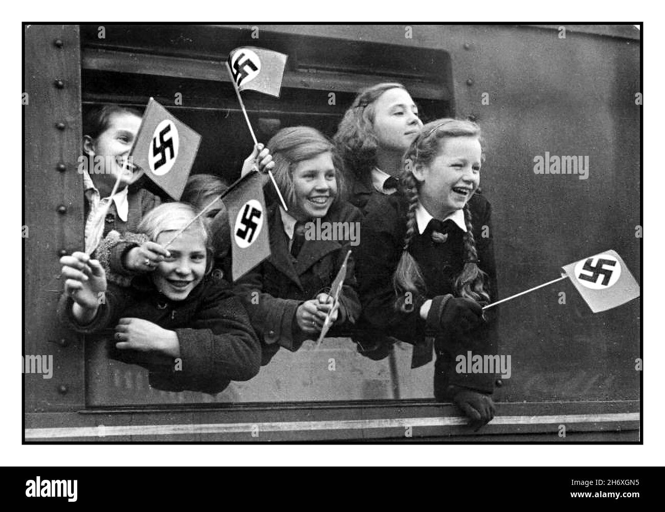 WW2 GERMANIA NAZISTA EVACUAZIONE BAMBINI KINDERTRANSPORTE KINDERLANDVERSCHICKUNG WW2 1940s evacuazione bambini in Germania durante la seconda guerra mondiale bambini tedeschi lasciare Berlino in un treno speciale 'Kindertransporte' sventolando bandiere naziste swastika nuovi trasporti giornalieri di bambini da tutte le zone della popolazione nella capitale del Reich come parte della terra Deportazione in altri distretti del Reich tedesco nazista, per proteggerli dai bombardamenti alleati DEI BAMBINI TEDESCHI WW2 Kinder Transport Vintage WW2 Germania nazista ‘ Kinderlandverschickung’ Propaganda Poster dal 1942 al 1943. Bombardamento alleato delle città tedesche Foto Stock