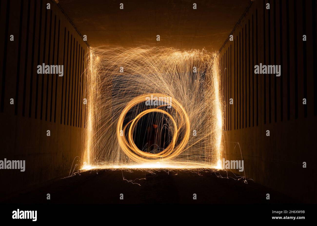 Pittura leggera con lana d'acciaio sul fuoco che roteare in un tunnel sottopasso nell'oscurità di notte, Scozia, Regno Unito Foto Stock