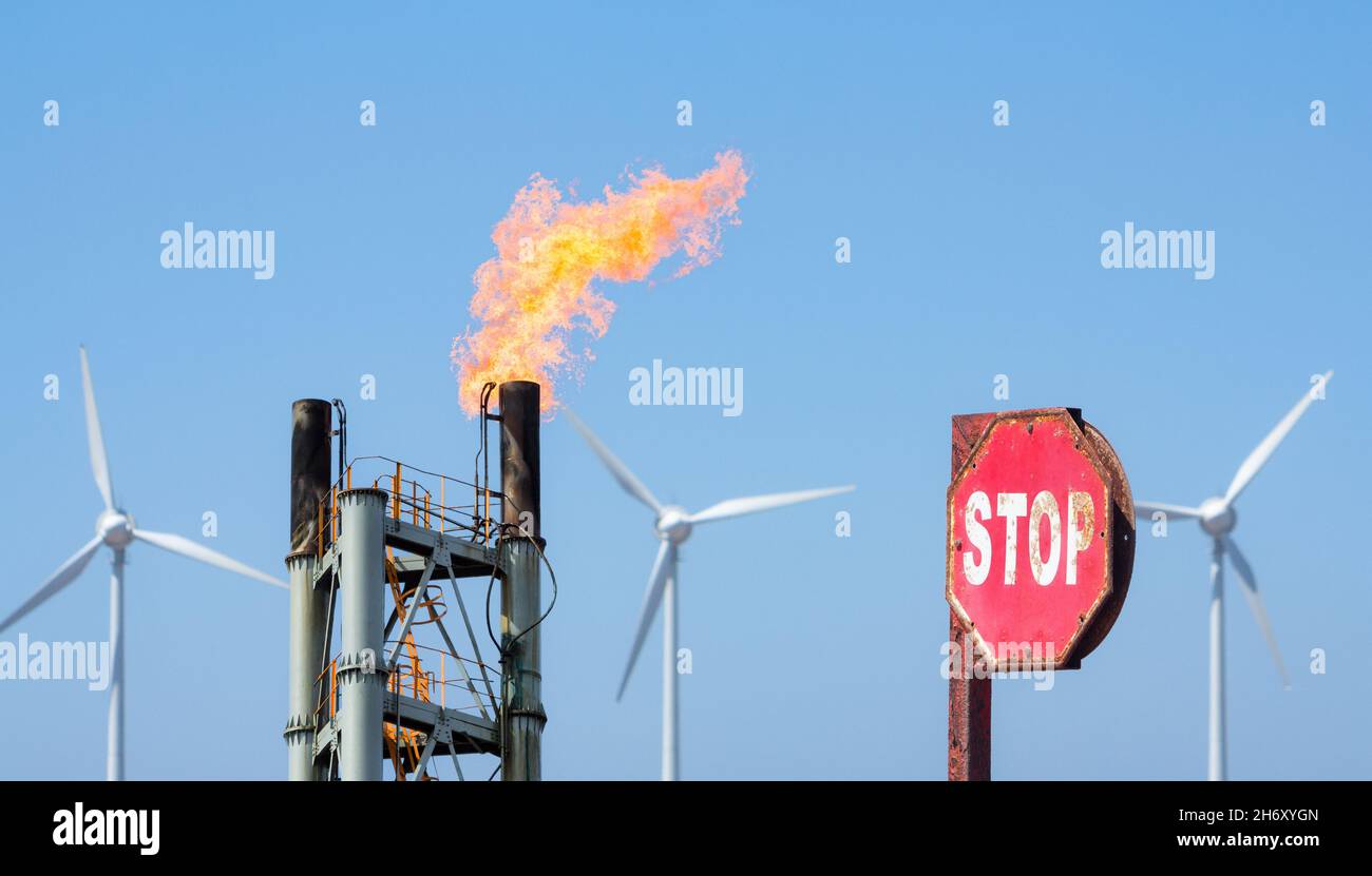 Impianto chimico gas flare con turbine eoliche e segnale di stop. Combustibili fossili, cambiamento climatico, riscaldamento globale, energia rinnovabile, inquinamento atmosferico... concetto Foto Stock