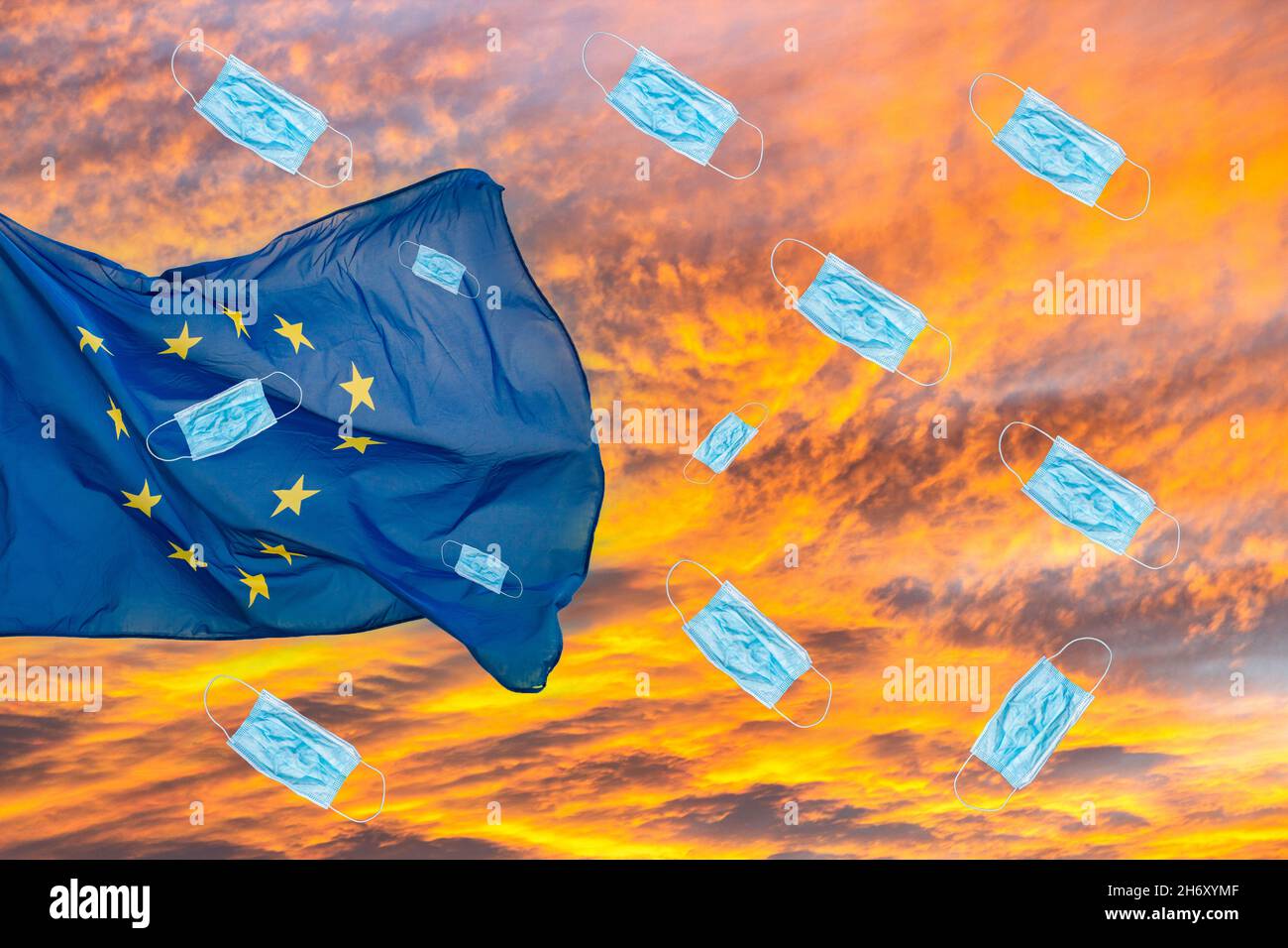 UE, bandiera dell'Unione europea contro il cielo del tramonto con le maschere facciali di Covid/Coronavirus che cadono dal cielo. I casi crescenti di Covid in Germania..., concetto europeo Foto Stock