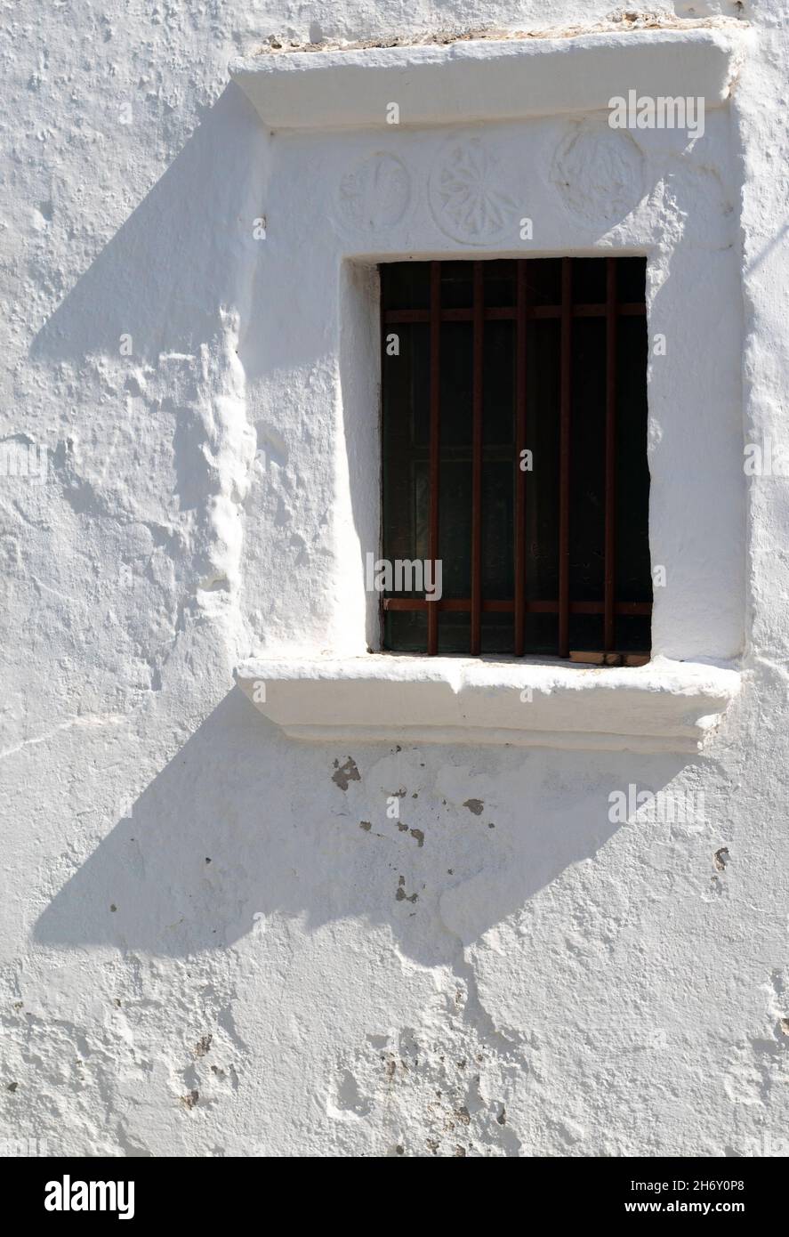 Vecchia chiesa sull'affascinante isola greca di Folegandros. Vista ravvicinata di una finestra con elementi scolpiti sull'architrave. Scatto verticale con spazio di copia. Foto Stock