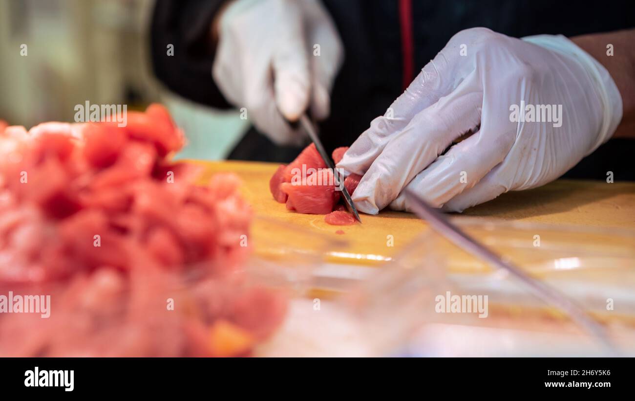 Venditore di cucina di sushi di tonno in via del mercato asiatico del pesce in Giappone. La gente cucinava il pesce popolare al famoso mercato di Tokyo. Deliziosi piatti giapponesi Foto Stock