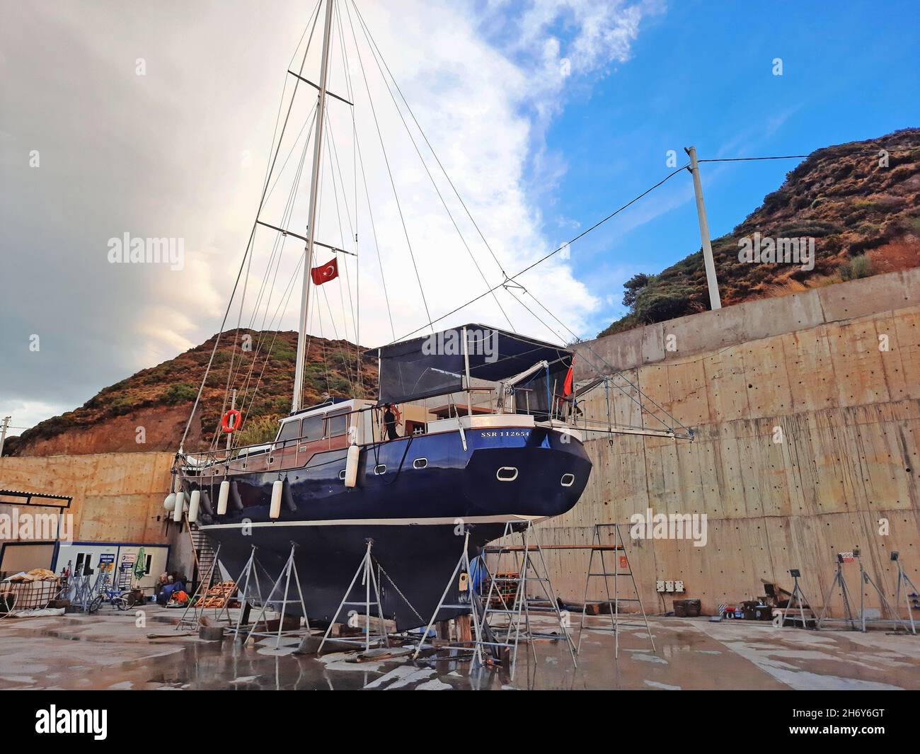 Bodrum, Turchia - 10.12.2021: Moderno yacht a vela presso il cantiere. Lo yacht sportivo è ancorato in un molo asciutto sulla riva del porto turistico. Marina di Kairos. Foto Stock