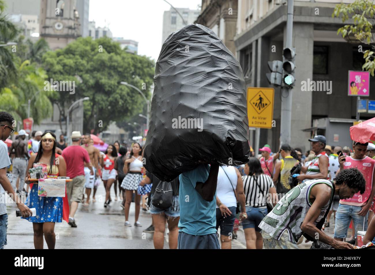 Americhe, Brasile – 22 febbraio 2020: Un uomo porta un grande sacco di rifiuti pieno di lattine usa e getta per il riciclaggio durante una sfilata di Carnevale a Rio de Janeiro Foto Stock