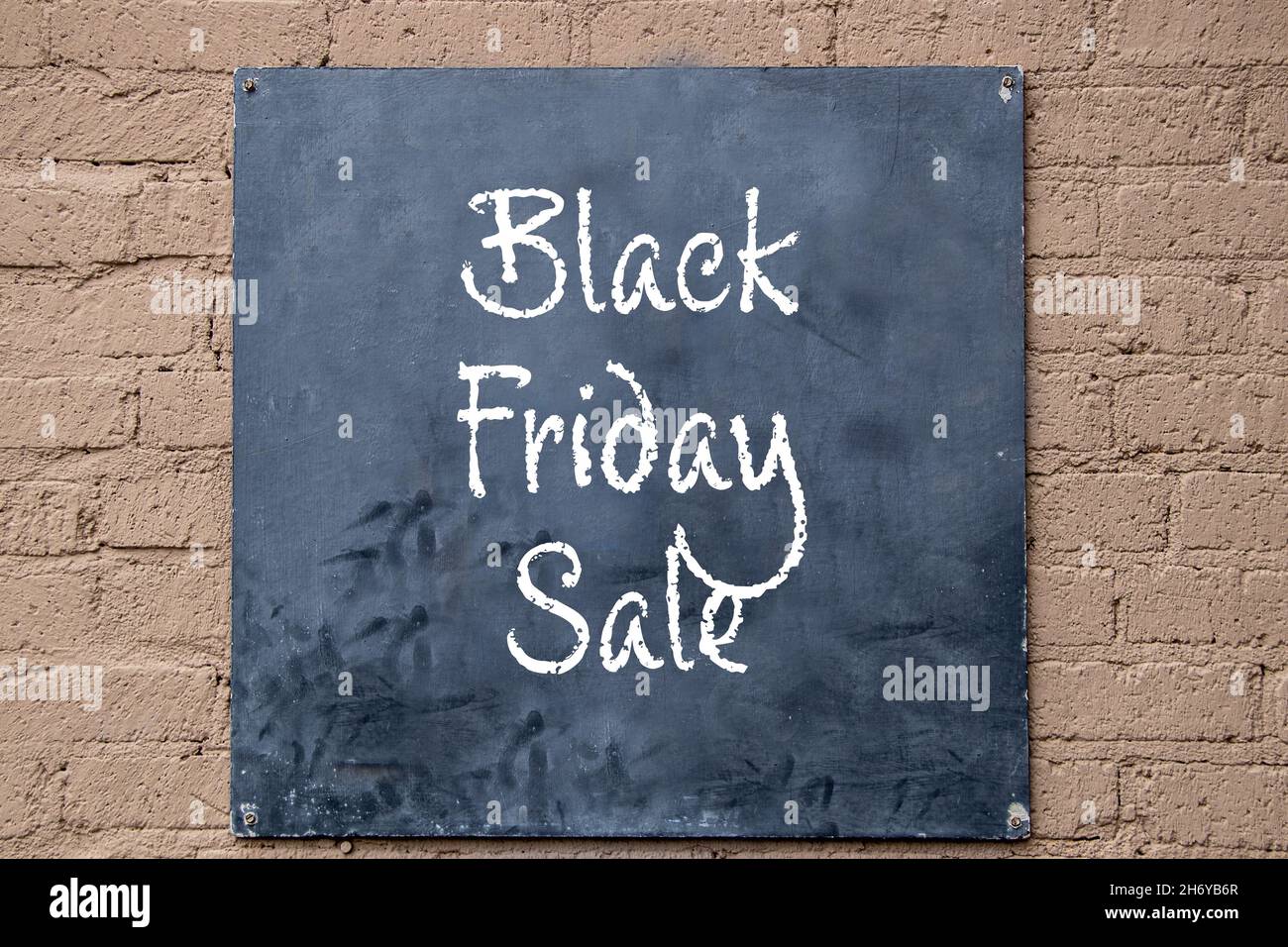 Cartello nero verniciato avvitato su muro di cemento verniciato -Nero Venerdì Vendita scritto in gesso Foto Stock