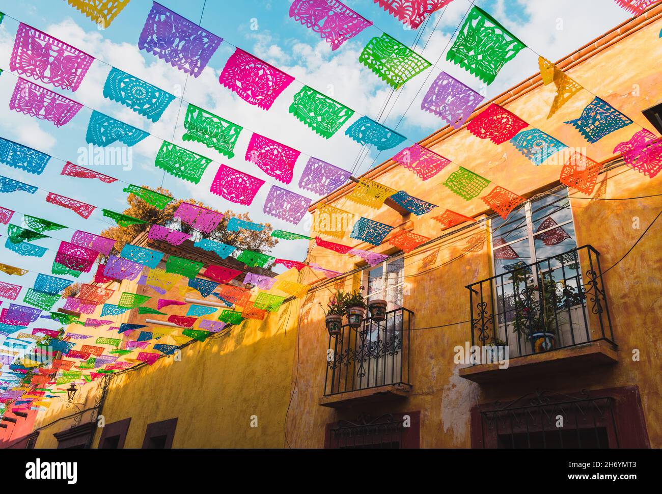 Bandiere di carta luminose e colorate su una strada in Messico in una giornata di sole. Foto Stock