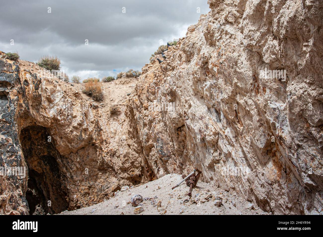 Tonopah, Nevada, Stati Uniti - 18 maggio 2011: Storico Parco minerario. Vecchia strada di fuga miniera, buca, scolata di roccia beige, pavimento del deserto sotto il paesaggio grigio nuvoloso. Foto Stock