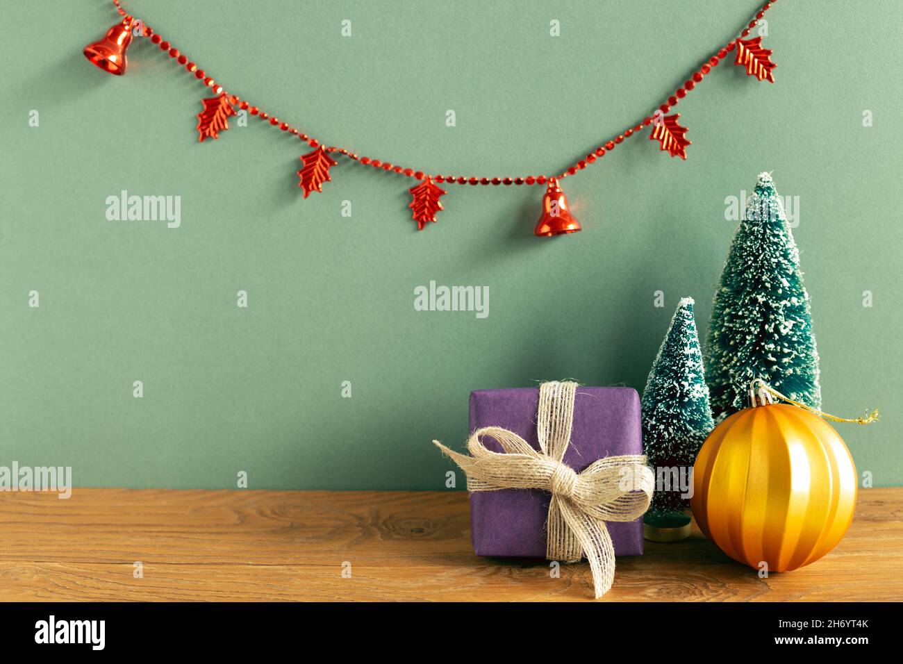 Inverno natale concetto. Scatola regalo, albero, bauble, garland partito su tavola di legno. Sfondo verde. Spazio copia Foto Stock