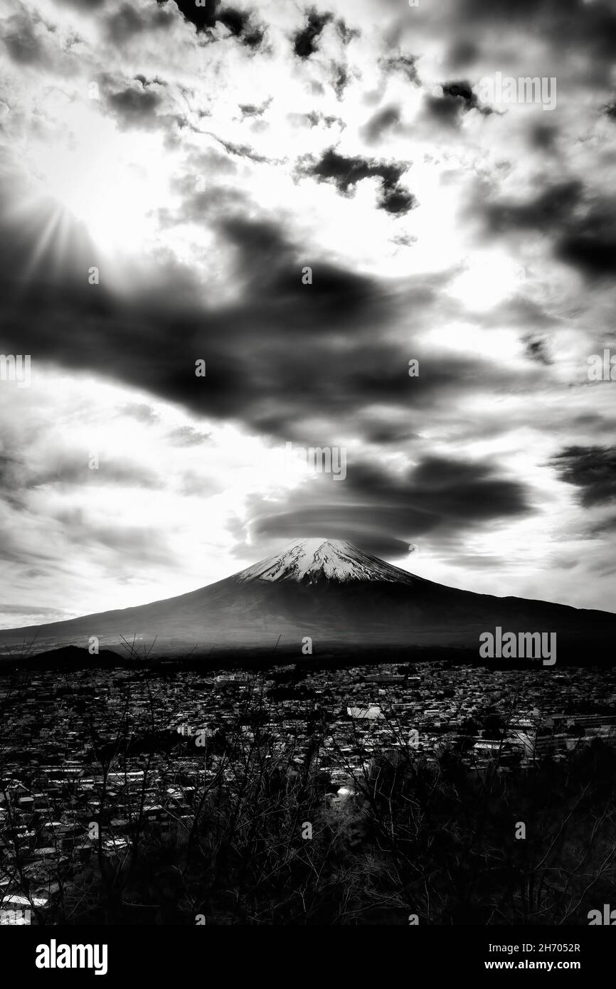 Le nuvole girano intorno alla cima del Monte Fuji e la città di Fujuyoshida, Giappone sottostante. Foto Stock