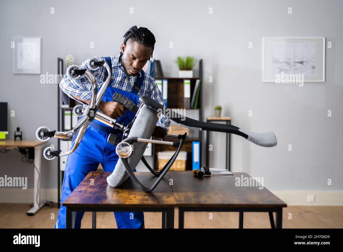 Assemblaggio e riparazione della sedia da ufficio. Uomo che lavora con lo strumento Foto Stock