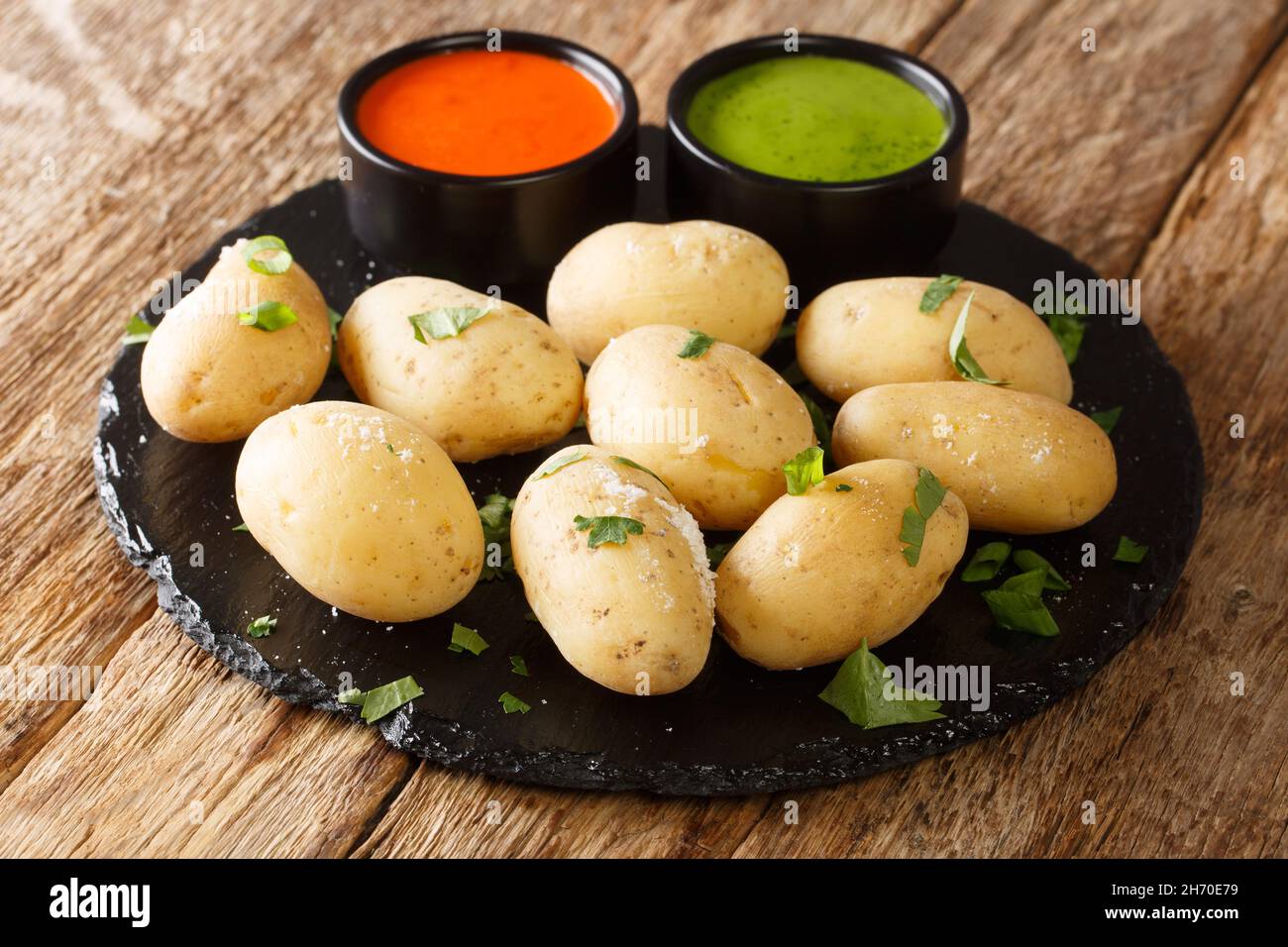 Patate rugose con salsa rossa e verde da vicino nel piatto sul tavolo. Orizzontale Foto Stock