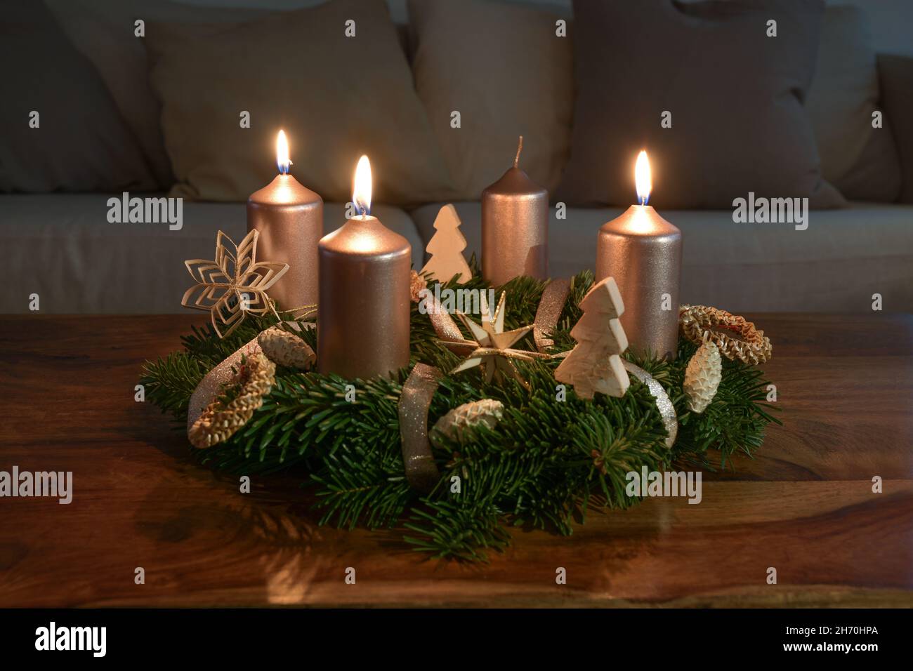 Terzo Avvento con tre candele dorate illuminate su una corona di Avvento con decorazione naturale di Natale su un tavolo da caffè in legno, spazio copia, fuoco selezionato, Foto Stock