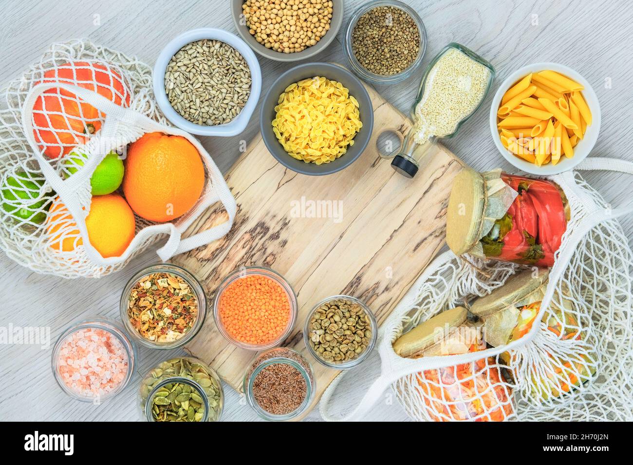 Cibo sano e dieta equilibrata concetto. Vari prodotti biologici agricoli in vasetti di vetro su sfondo di legno chiaro. Vista dall'alto, spazio di copia. Foto Stock