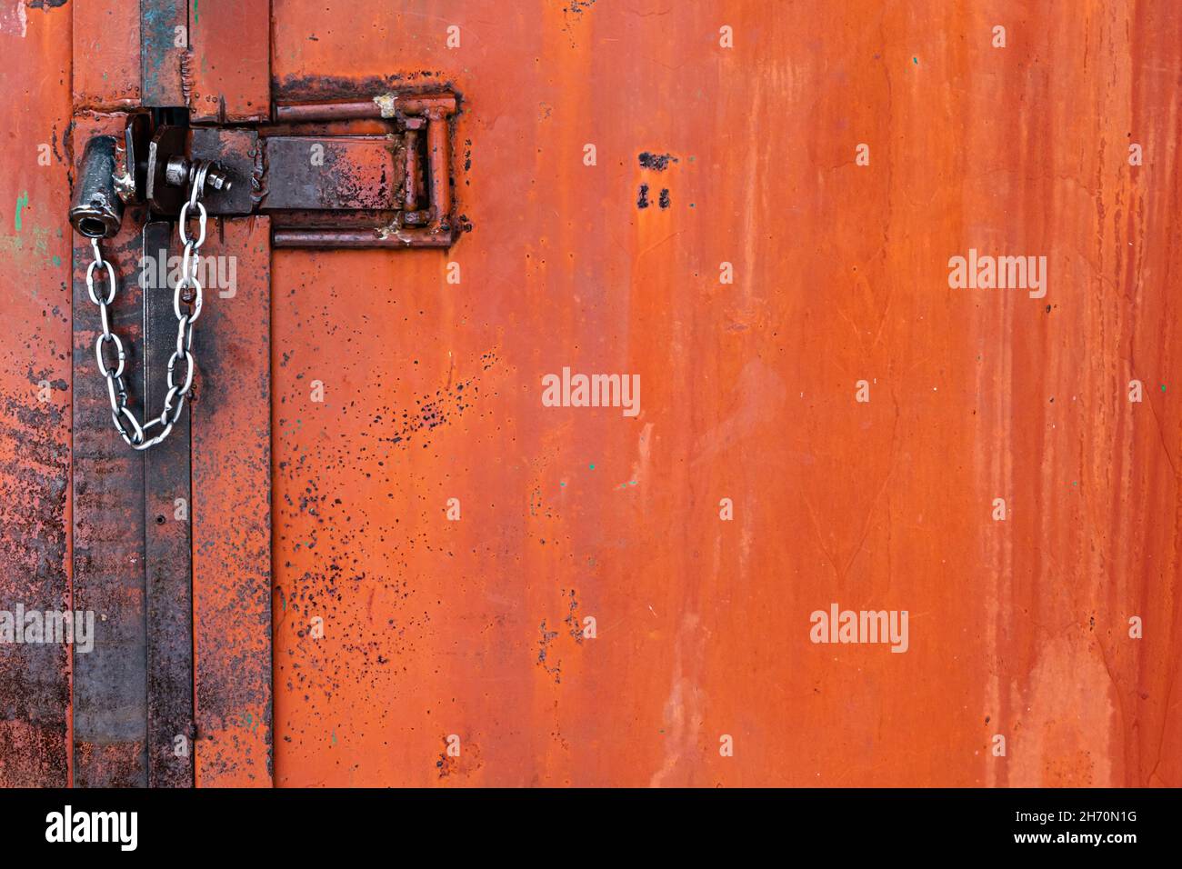 Vecchia porta arancione in ferro arrugginito con serratura, parti  metalliche, chiavistello, dadi e catena lucida. Messa a fuoco selettiva.  Primo piano Foto stock - Alamy