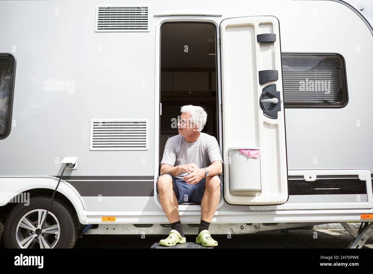 Uomo seduto alla porta caravan Foto Stock