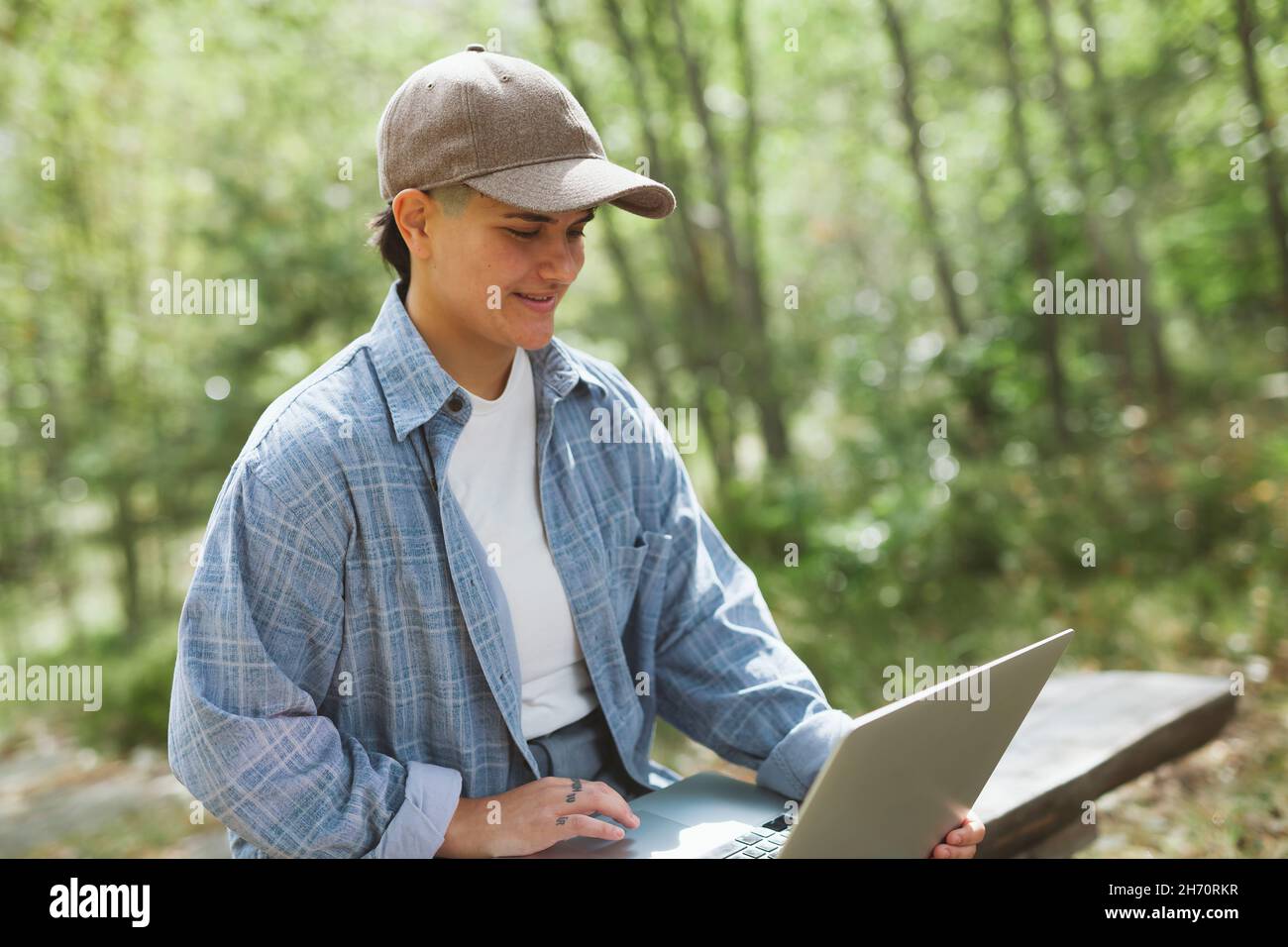 Giovane donna con computer portatile seduto su panca Foto Stock