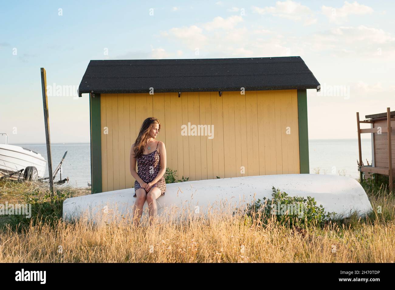 Giovane donna seduta dietro la capanna della spiaggia Foto Stock