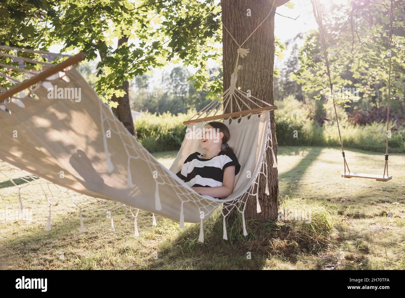 Ragazza sdraiata in amaca in giardino Foto Stock