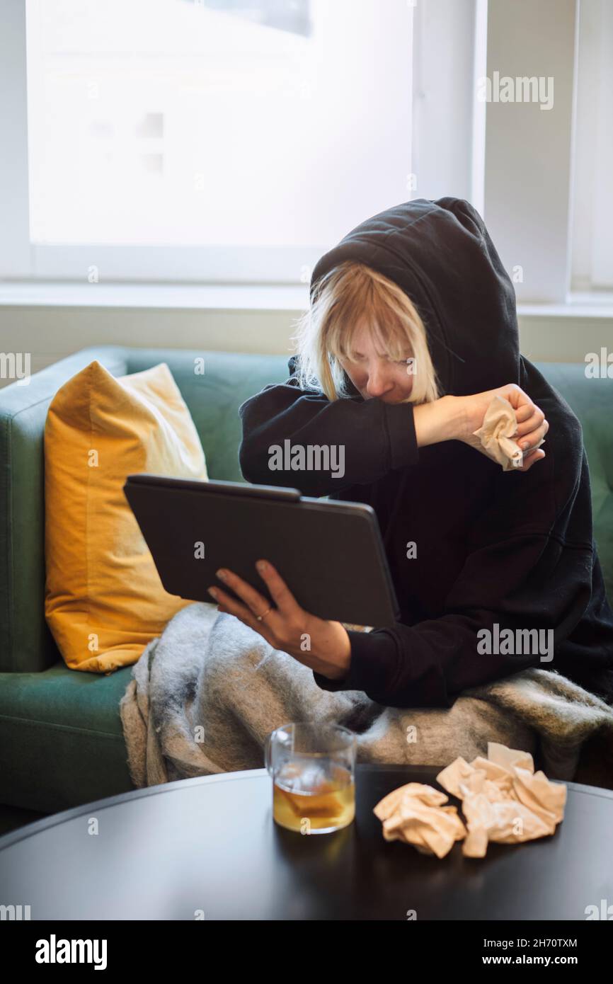 Donna malata sul divano con tablet digitale Foto Stock