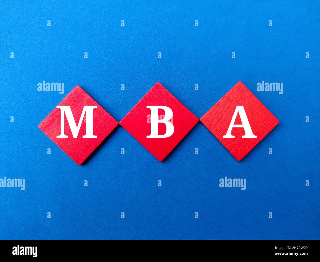 Cubo di legno colorato scritto con testo MBA su sfondo blu. Foto Stock