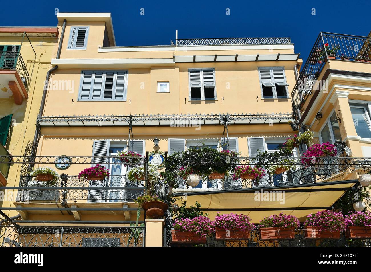 Facciata di una tipica casa che si affaccia sul lungomare di Alassio con balconi fioriti in una soleggiata giornata estiva, Savona, Liguria, Italia Foto Stock