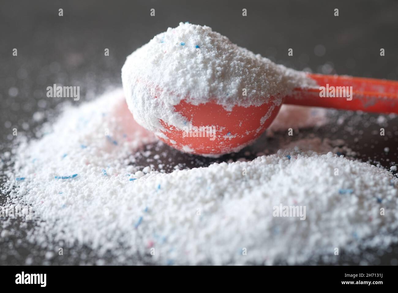 Polvere di lavaggio in cucchiaio di plastica su sfondo nero vista dall'alto. Foto Stock