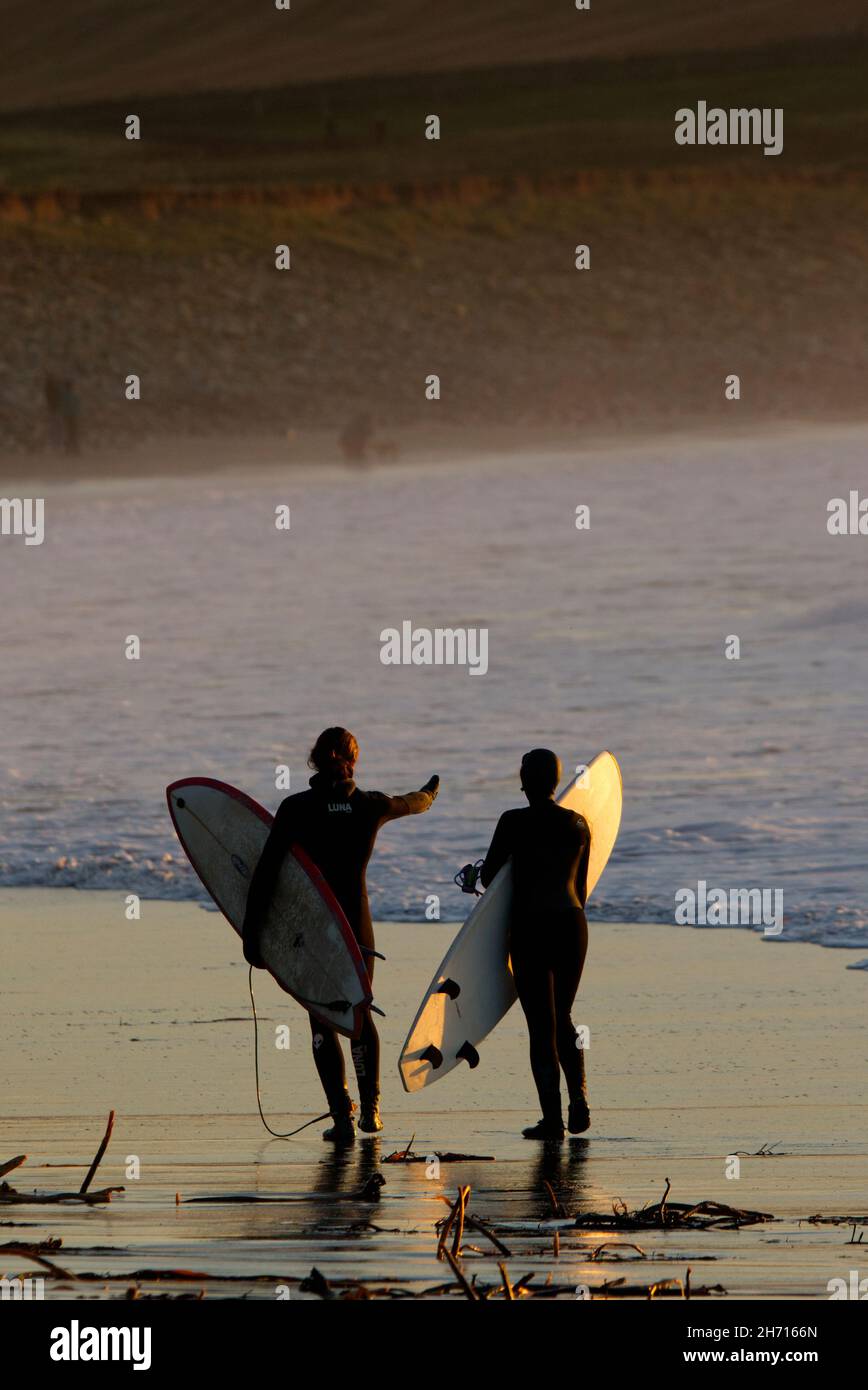 Surfers camminando lungo la costa, Skaill, Orkney Foto Stock