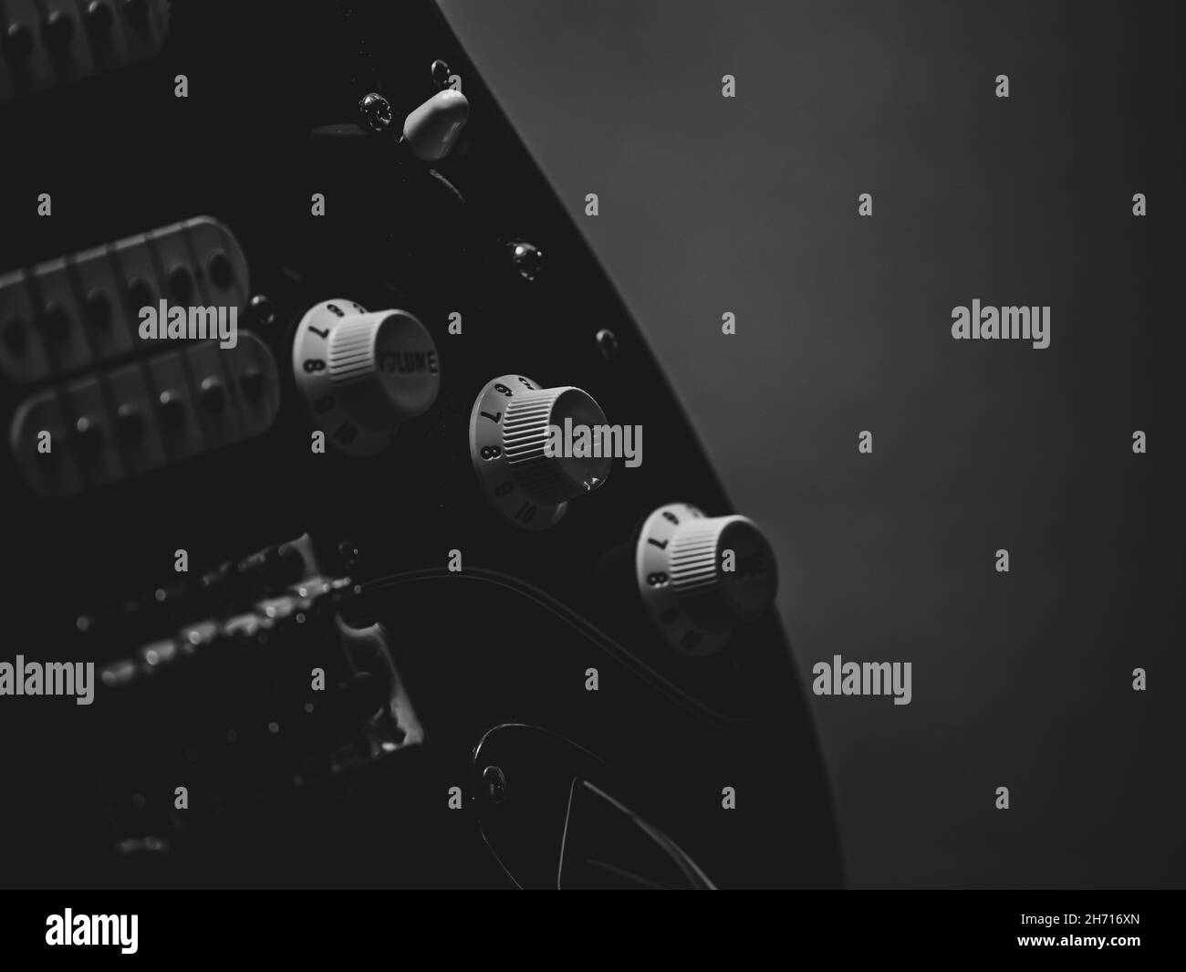 Foto in scala di grigi con manopole per volume e tono su una chitarra elettrica Fender Foto Stock