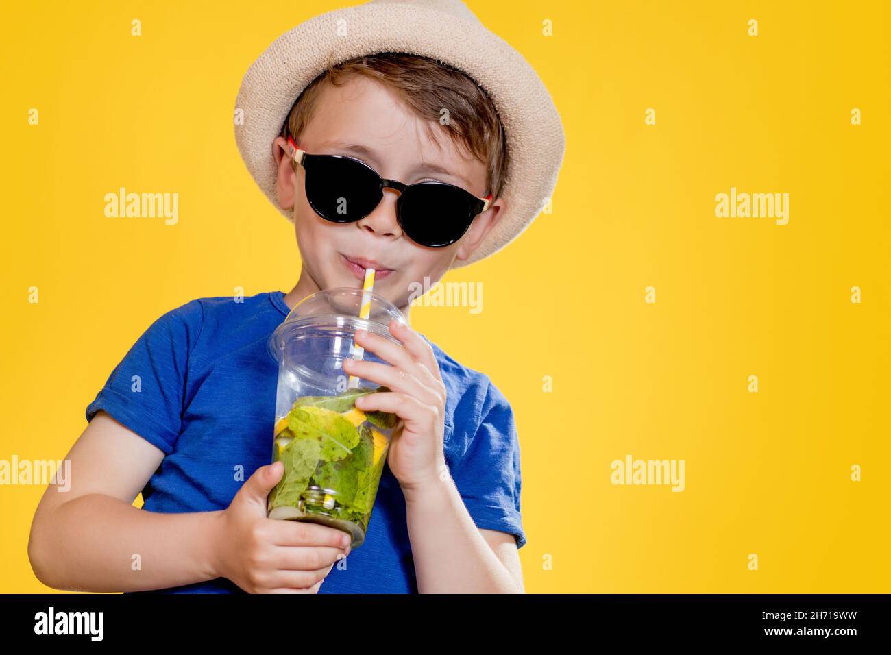 Ragazzo in estate vestito con occhiali da sole e godendosi mentre beve un  cocktail Mojito. Posa su sfondo giallo Foto stock - Alamy