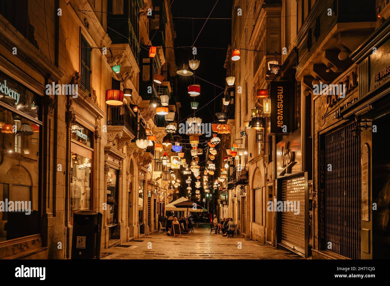 Valletta, Malta-Ottobre 18,2021. Sera strada con bar, negozi e ristoranti illuminati da lanterne vintage colorate. Vita notturna della città. Street festive Foto Stock