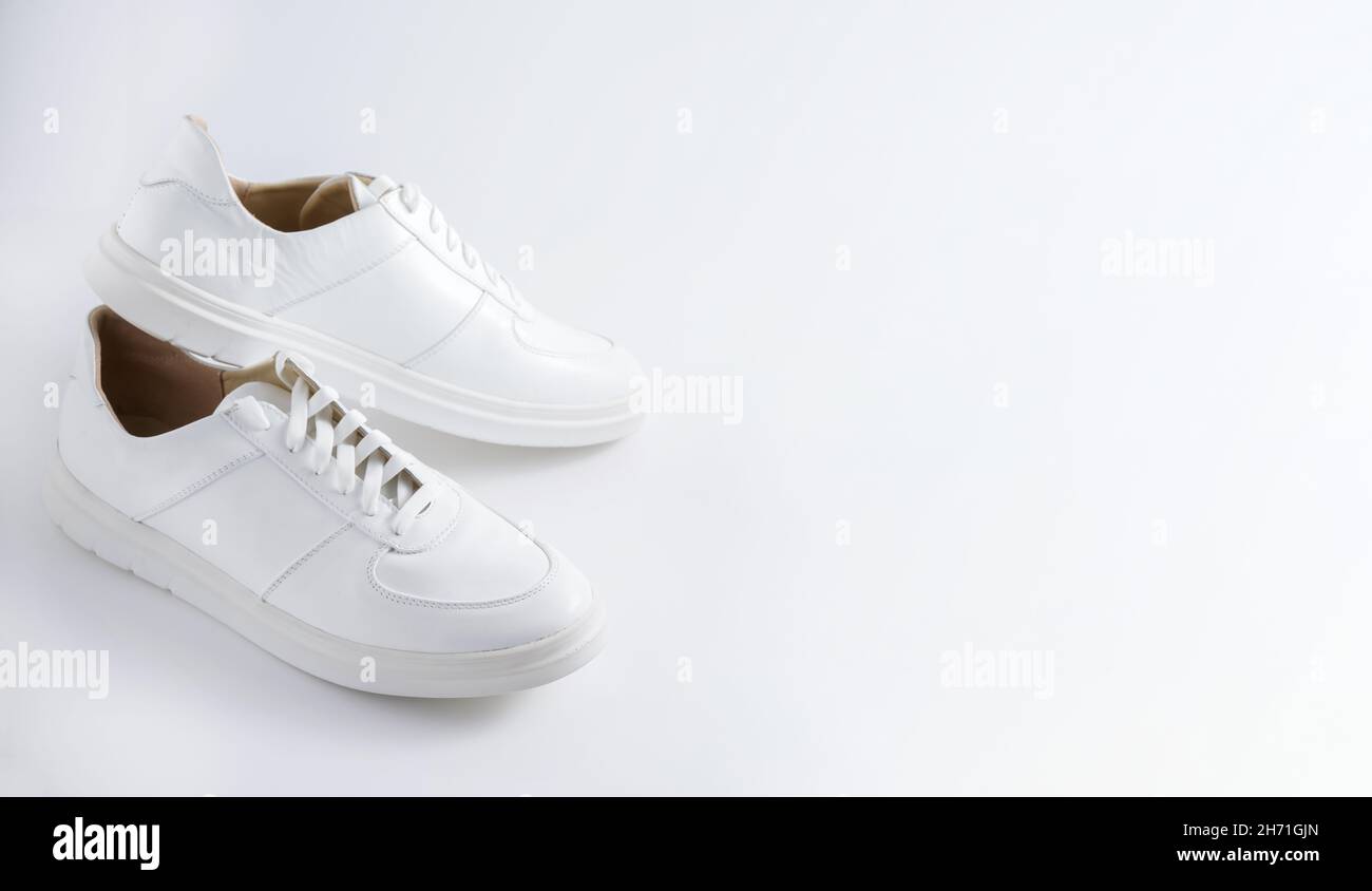 Sneaker bianche isolate su sfondo bianco. Banner con spazio di copia. Scarpe sportive comode. Stile casual UNISEX. Un paio di sneaker classiche. Tendenza scarpe in pelle per tutta la stagione. Sneaker con lacci bianchi. Foto Stock