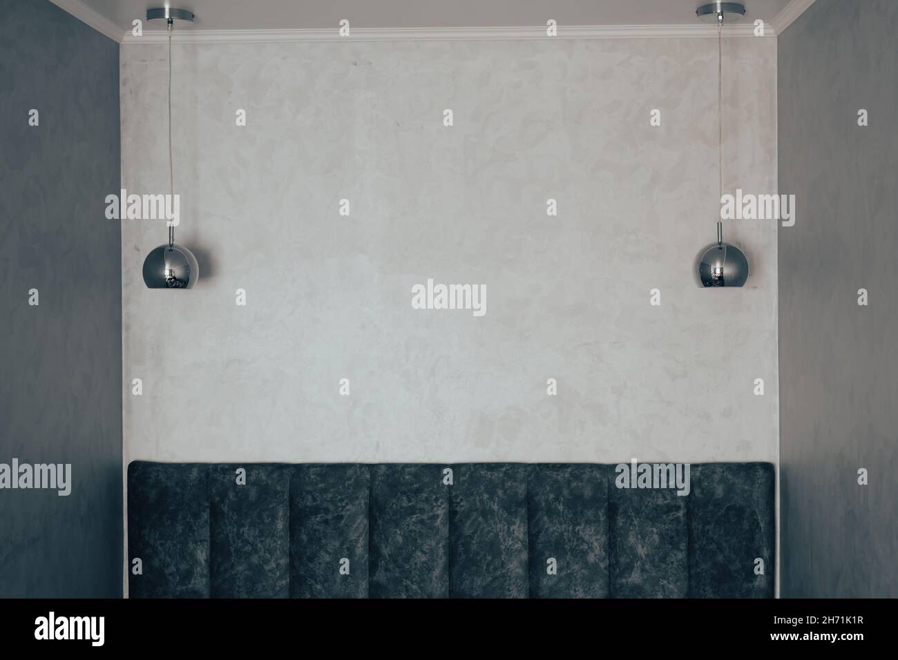 Le luster a forma di sfera d'argento sono appese sul divano vicino alla parete grigia Foto Stock