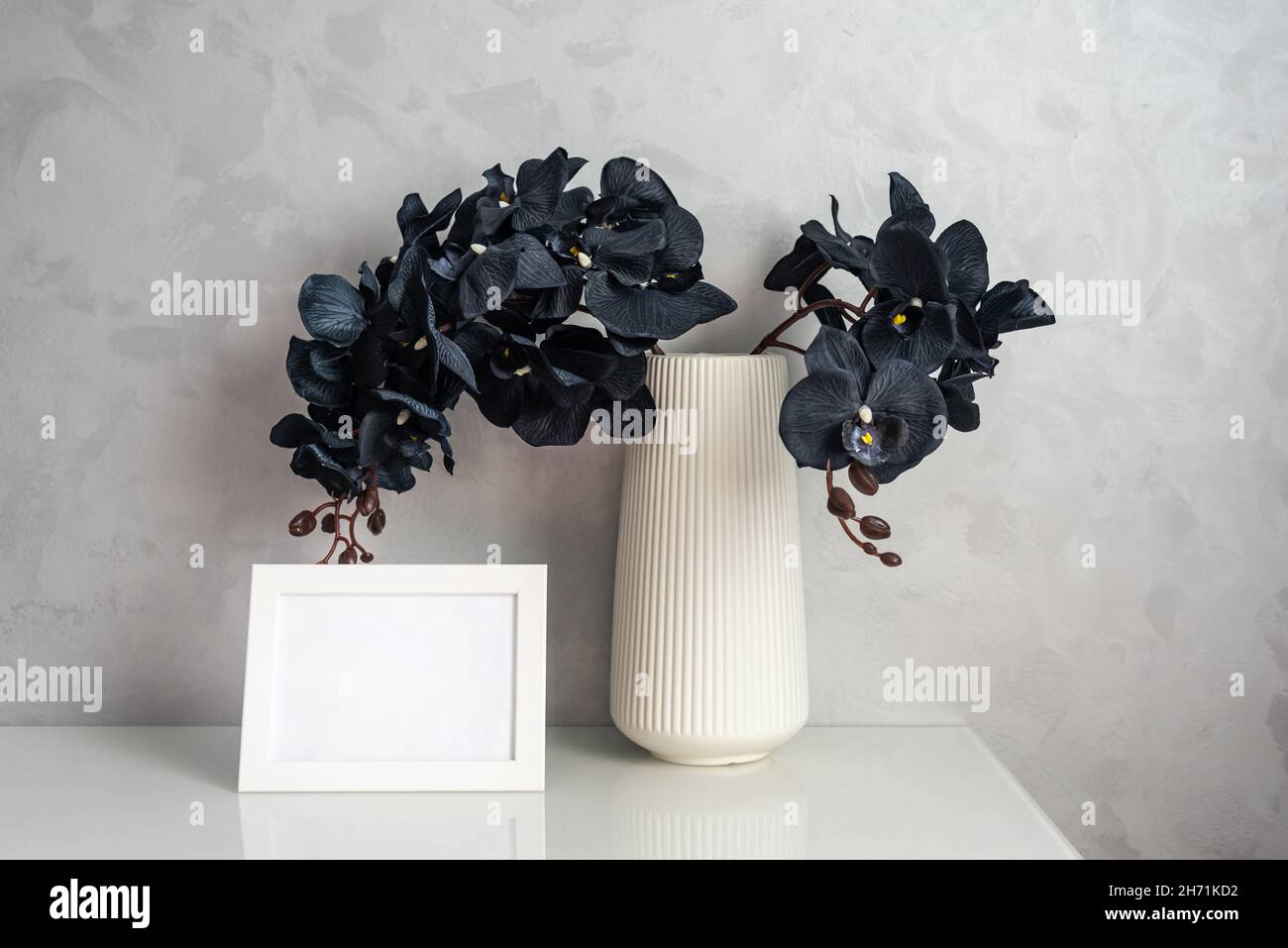 Fiori di Orchidea con petali neri e photoframe sul cabinet Foto Stock