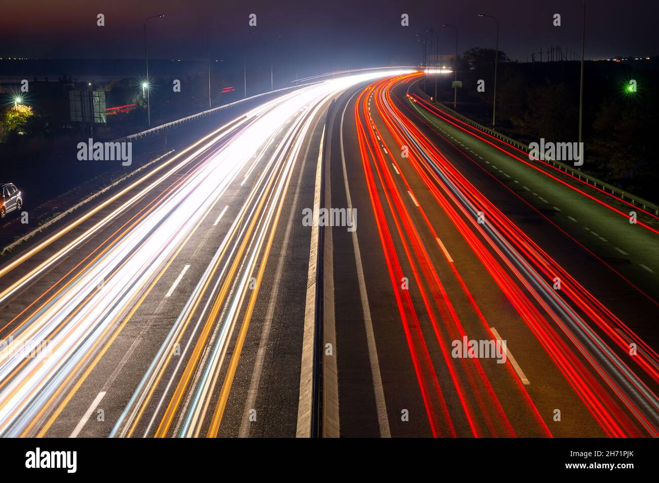 Autostrada suburbana di notte. Tracce di traffico intenso dai fari anteriori e dalle luci di posizione posteriori Foto Stock
