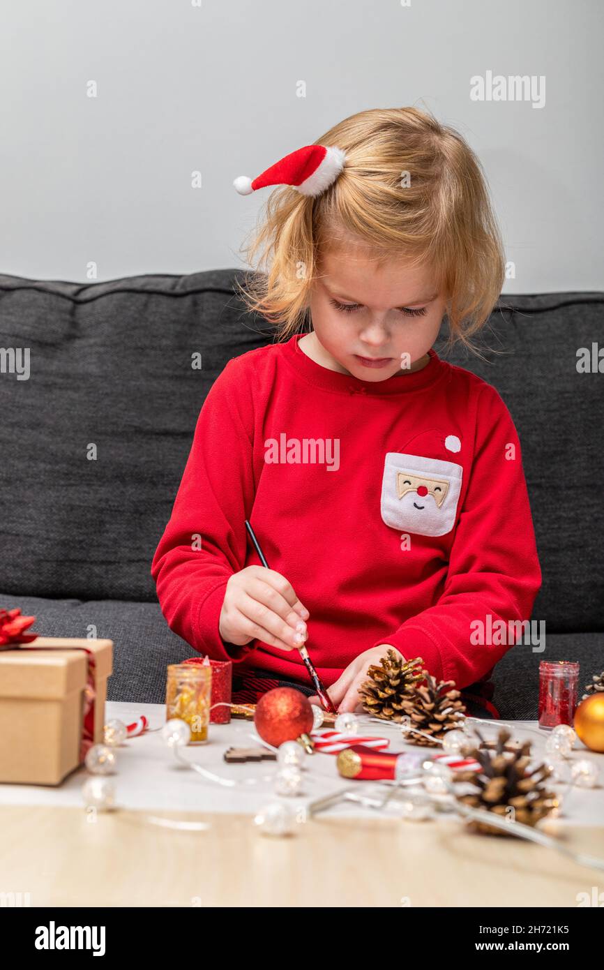 Bambino piccolo che indossa pigiama di festa di natale, facendo le decorazioni dell'albero di Natale di mestieri. Foto Stock