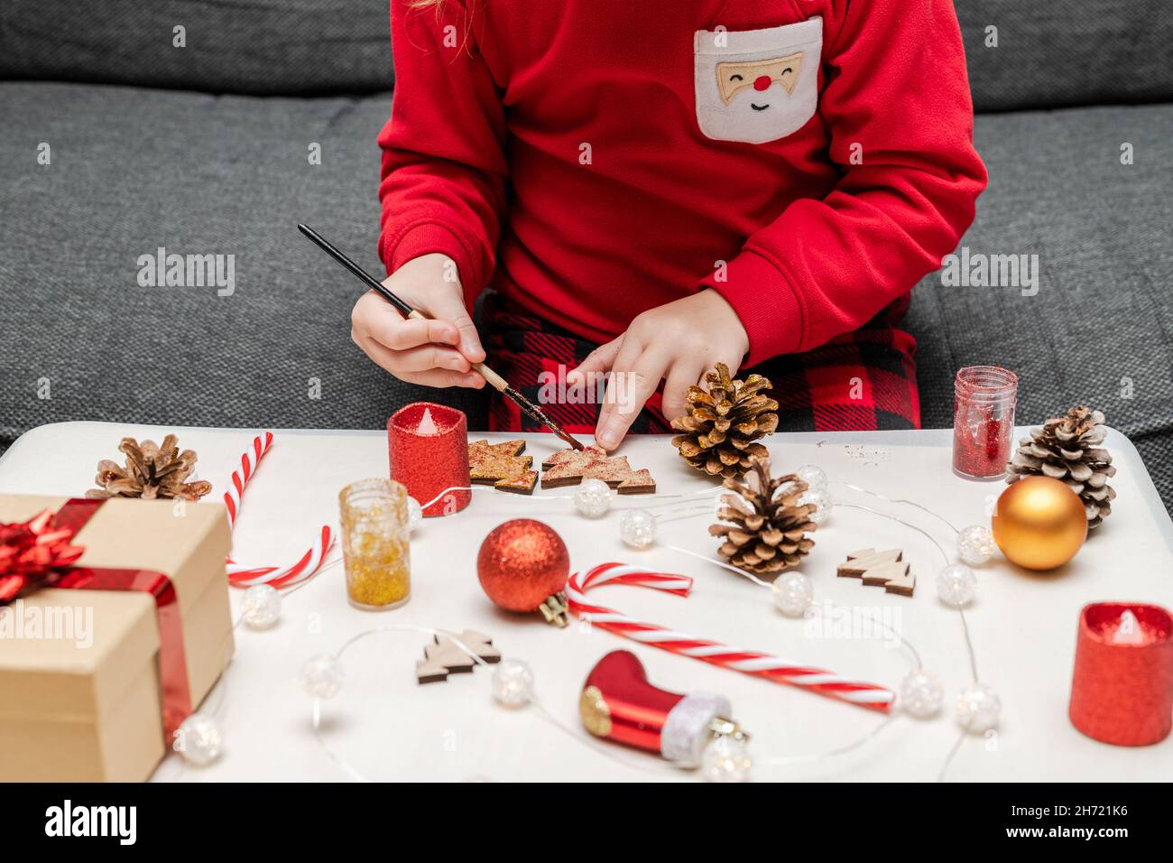Bambino piccolo che indossa pigiama di festa di natale, facendo le decorazioni dell'albero di Natale di mestieri. Foto Stock