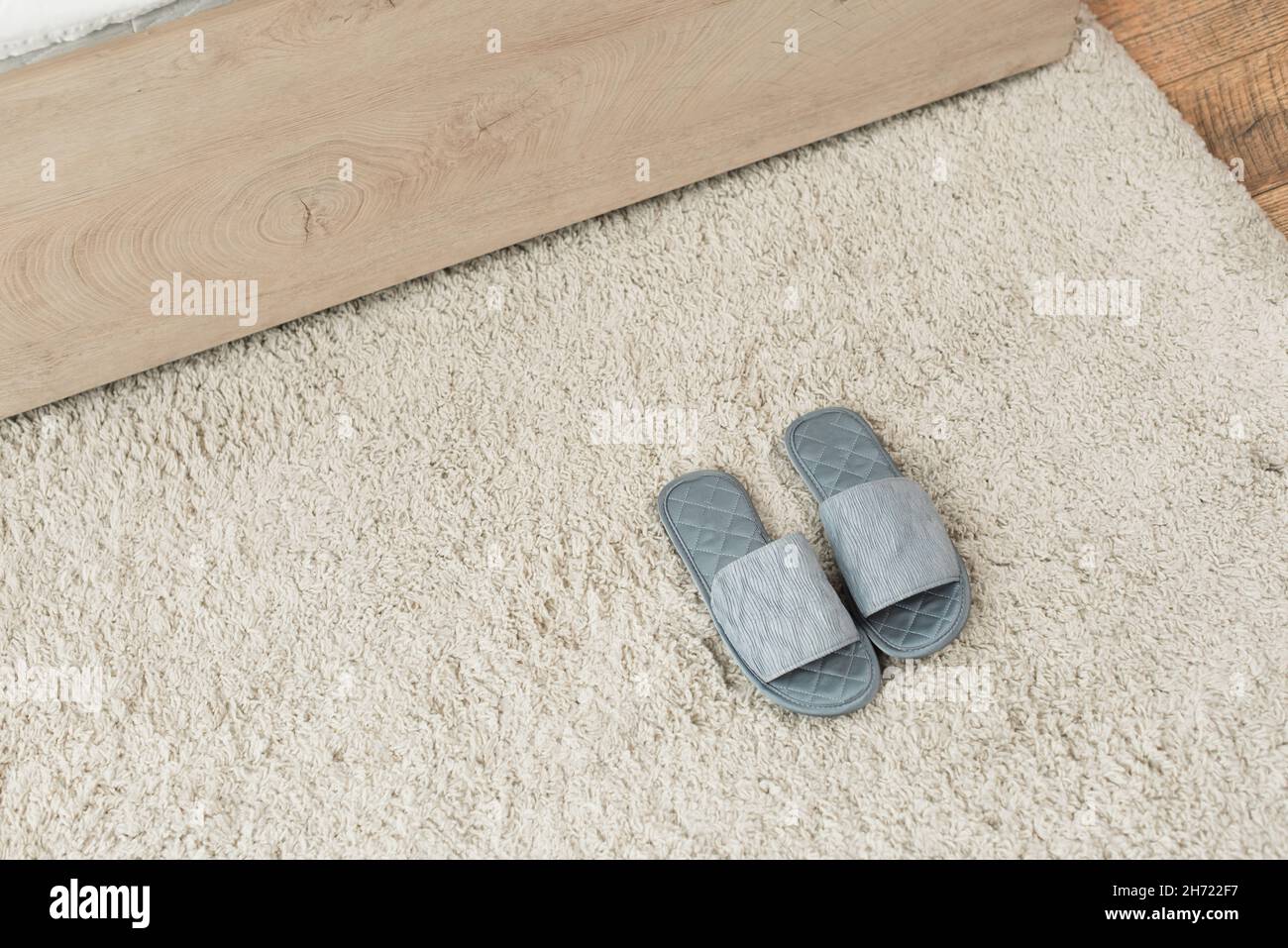 vista ad angolo alto delle pantofole grigie su tappeto beige Foto Stock