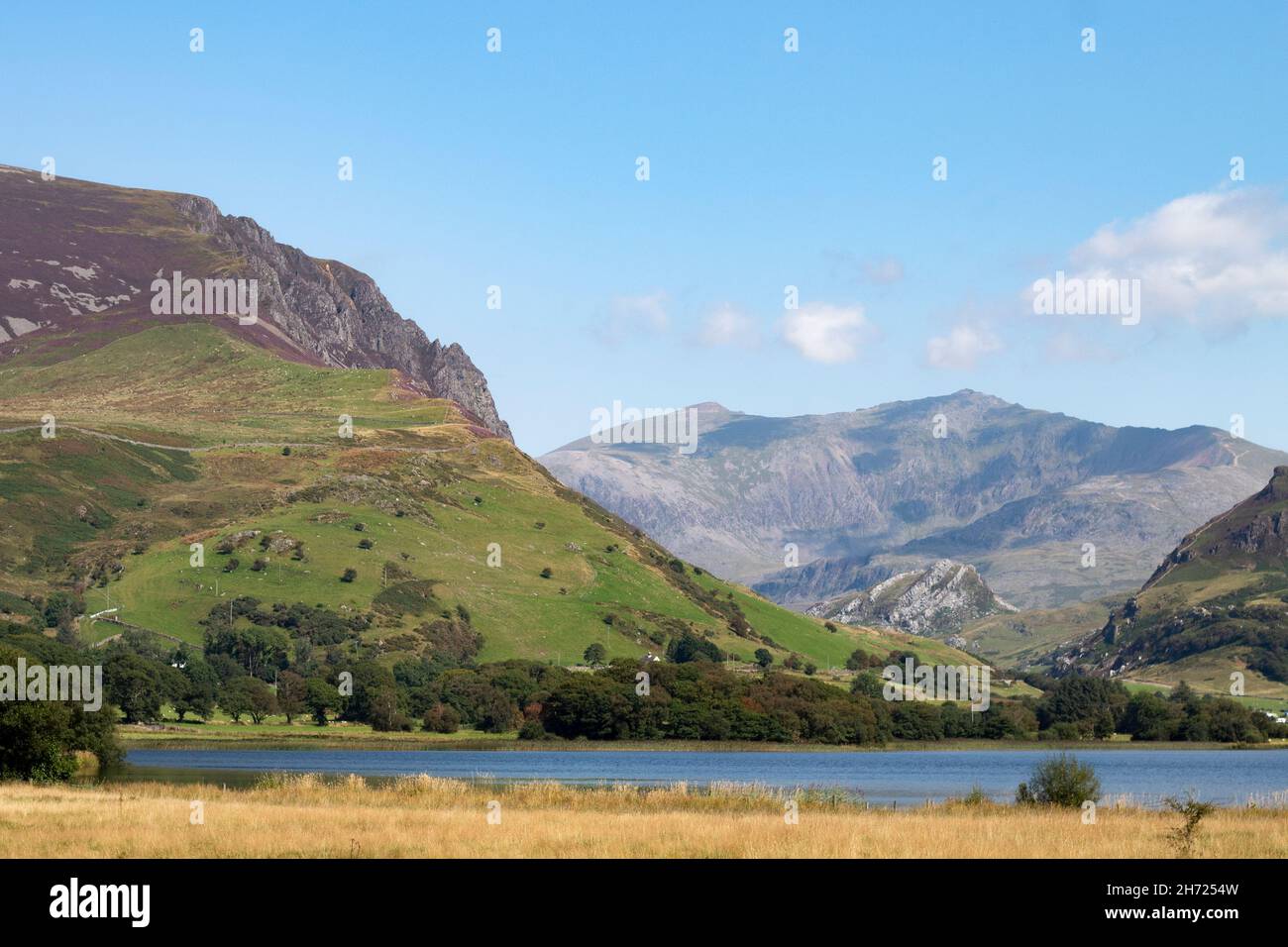 Bellissimo lago Nantlle, Snowdonia, Galles. Panorama con primo piano di acqua e prato. Spettacolare e robusto Mount Snowdon sullo sfondo. Orizzontale A. Foto Stock