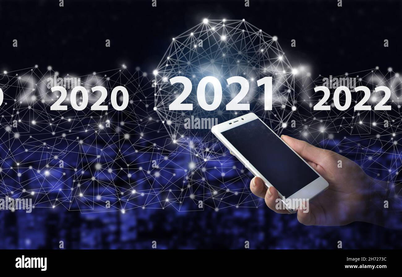 Concept Start Capodanno 2021 smartphone bianco portatile con ologramma digitale 2021 icona città scuro sfondo sfocato. Benvenuti anno 2021 Business New YE Foto Stock